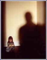 shadowy figure menaces crouching child